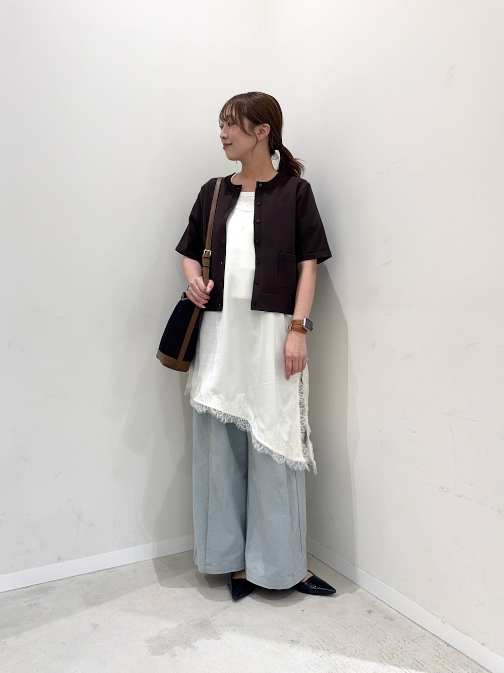 ブラウン系のカーディガン/ボレロ、ホワイト系のキャミソール、ブルー系のデニムパンツを着用したレディースの春コーディネートの1枚目の写真