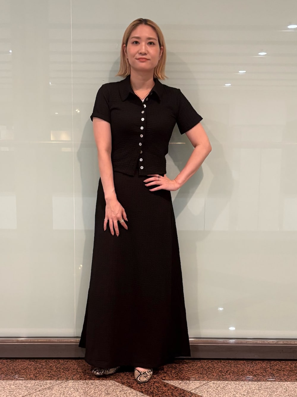 ブラック系のポロシャツ、ブラック系のスカートを着用したレディースの夏コーディネートの1枚目の写真