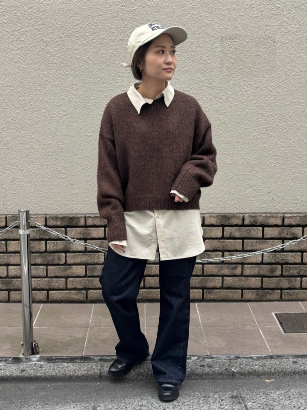 ブラウン系のニット/セーター、ホワイト系のシャツ/ブラウス、ブルー系のデニムパンツを着用したレディースの秋コーディネートの1枚目の写真