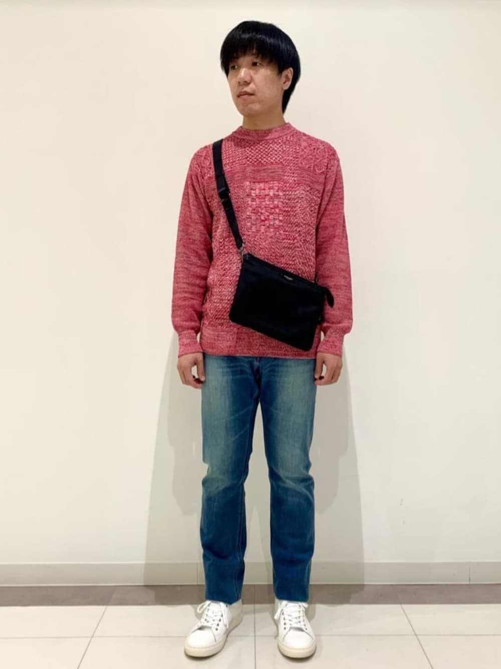 ホワイト系のスニーカー、ピンク系のニット/セーター、ブルー系のデニムパンツを着用したメンズの冬コーディネートの1枚目の写真