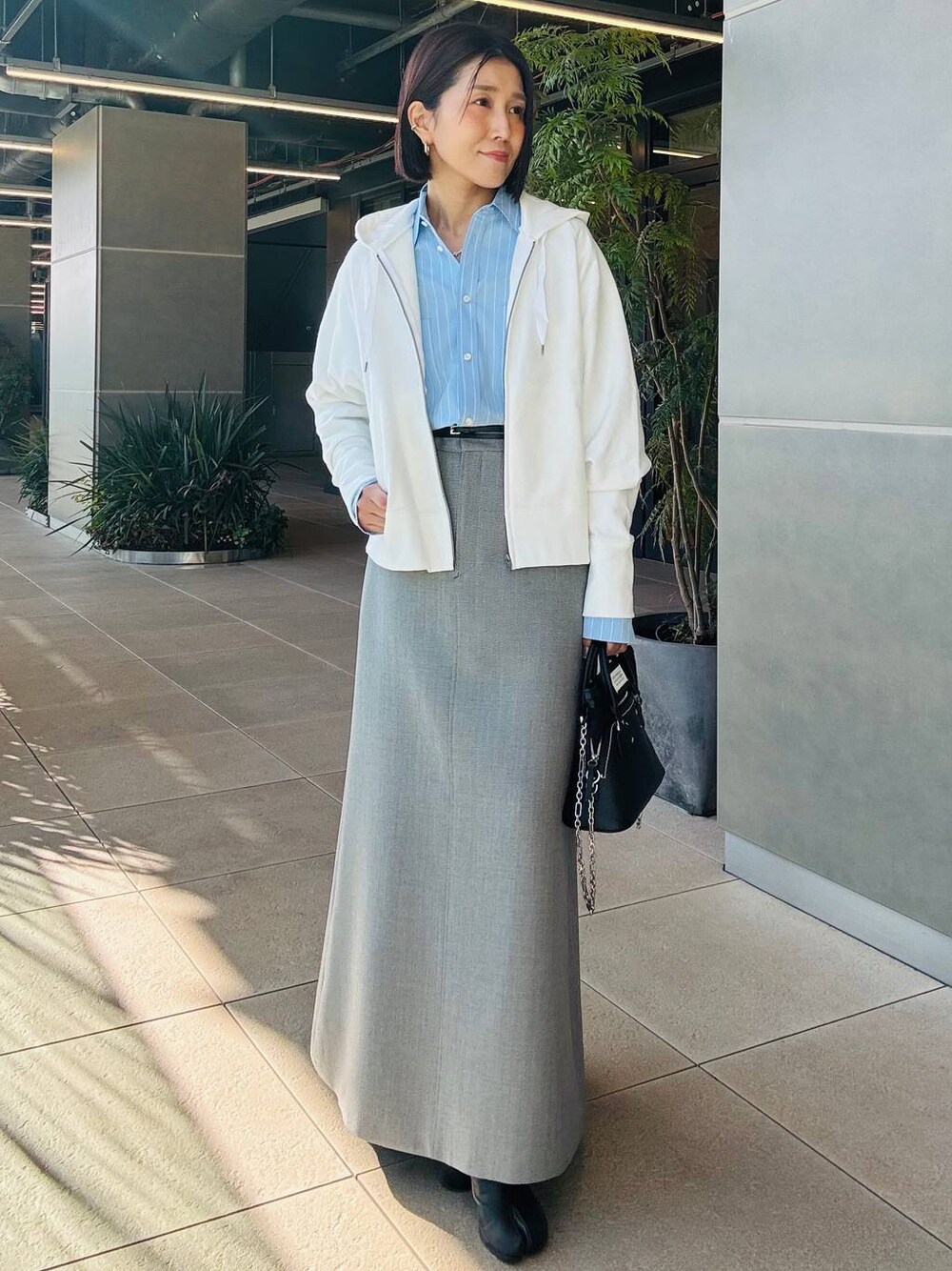 ホワイト系のパーカー、グレー系のスカートを着用したレディースの冬コーディネートの1枚目の写真