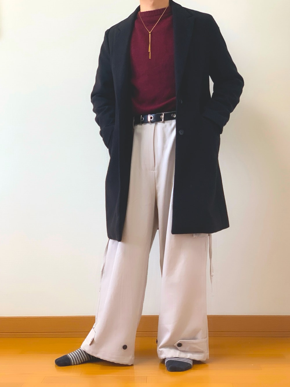 レッド系のニット/セーター、グレー系のカーゴパンツ、ブラック系のステンカラーコートを着用したメンズの冬コーディネートの1枚目の写真