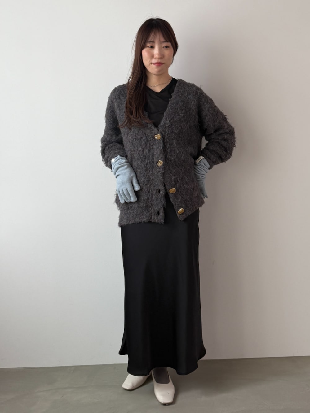 ブラウン系のカーディガン/ボレロ、ブラック系のスカート、ブルー系の手袋を着用したレディースの秋コーディネートの1枚目の写真