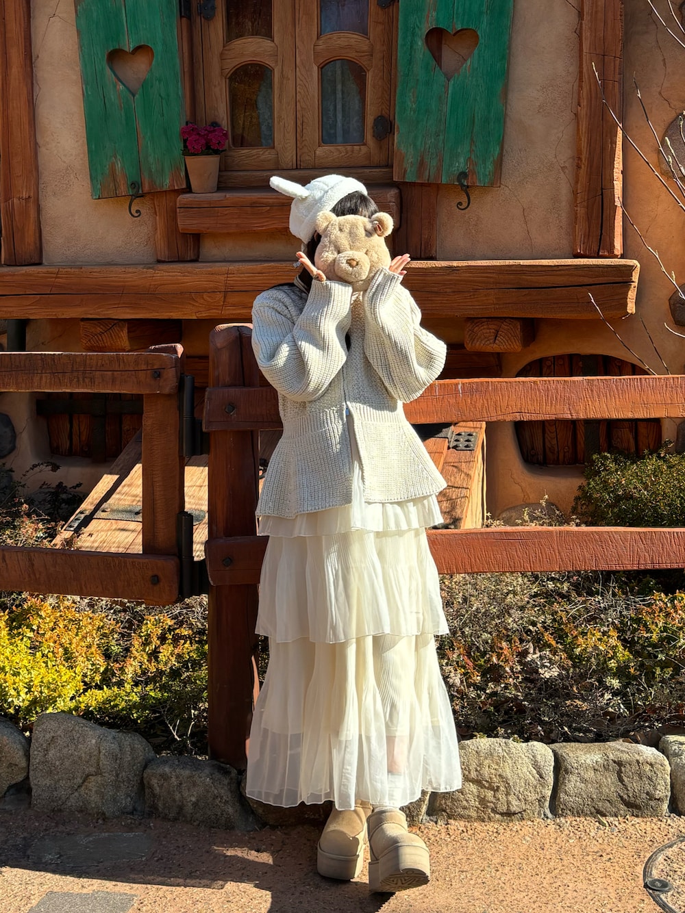 ホワイト系のカーディガン/ボレロ、ピンク系のニット/セーター、ホワイト系のスカートを着用したレディースの冬コーディネートの1枚目の写真