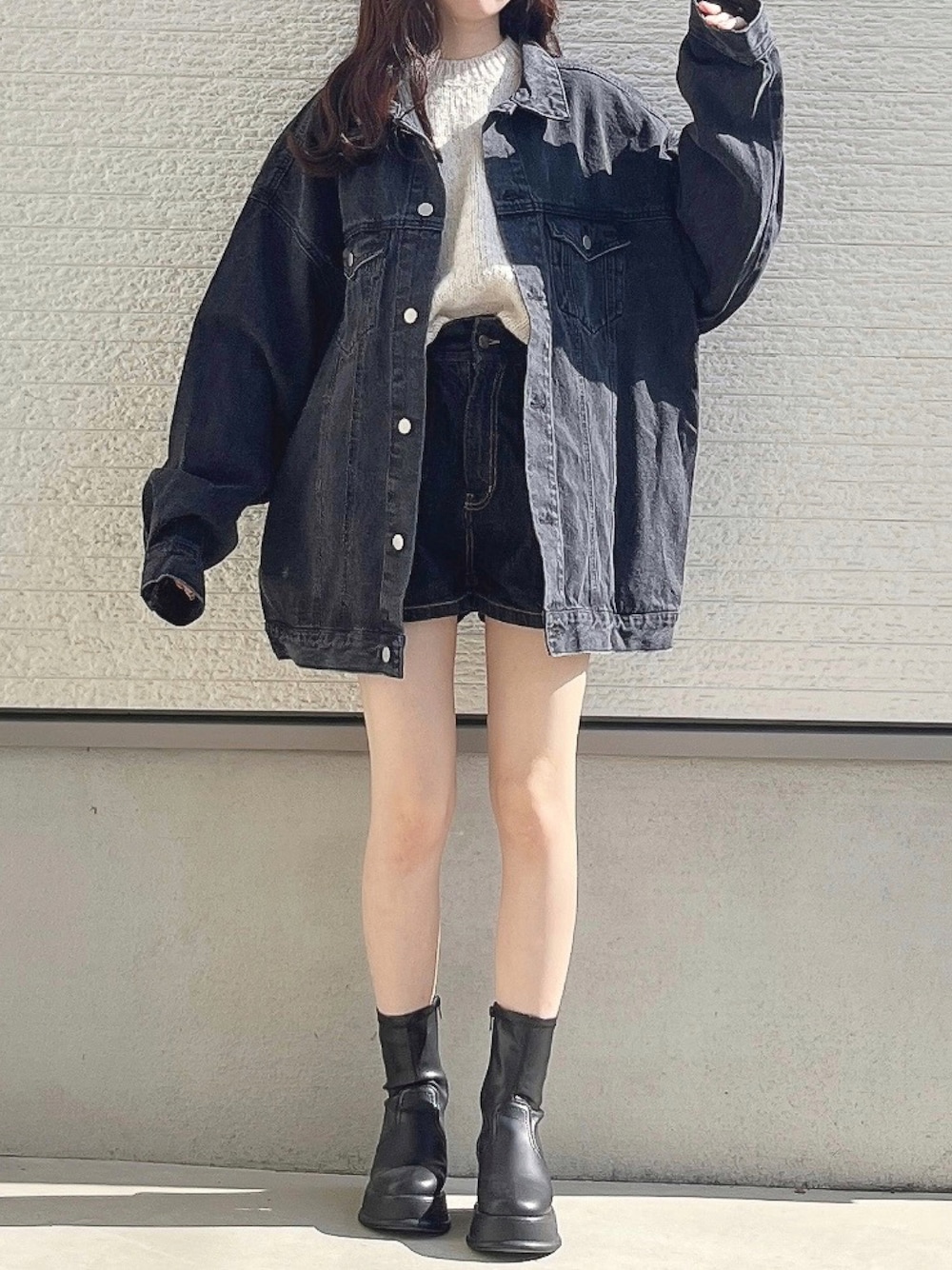 ブラック系のデニムジャケット、ホワイト系のニット/セーター、ブラック系のデニムパンツを着用したレディースの秋コーディネートの1枚目の写真