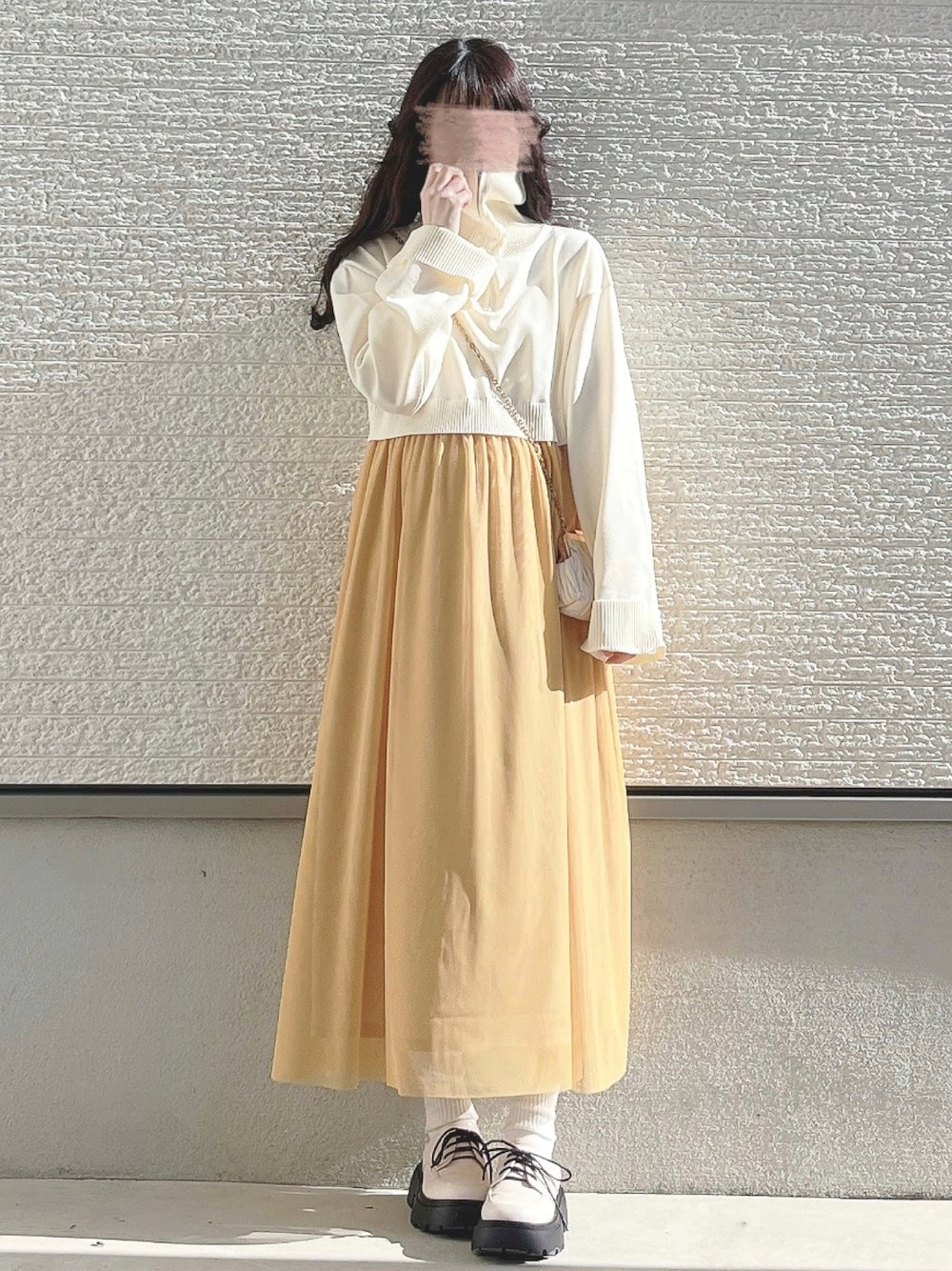 ベージュ系のショルダーバッグ、ホワイト系のパンプスを着用したレディースの冬コーディネートの1枚目の写真