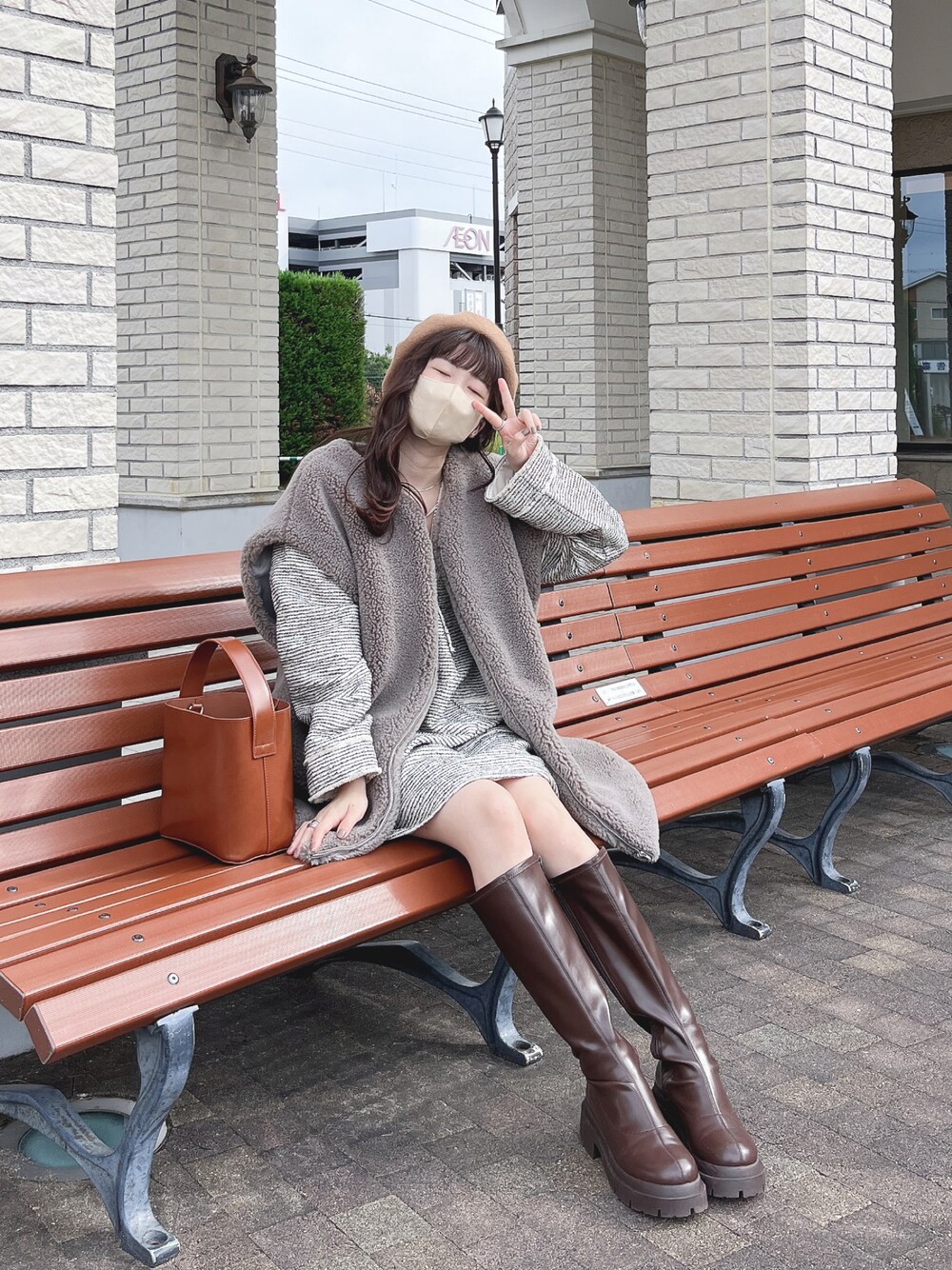 グレー系のベスト、ベージュ系のその他トップス、ブラウン系のハンドバッグを着用したレディースの秋コーディネートの1枚目の写真