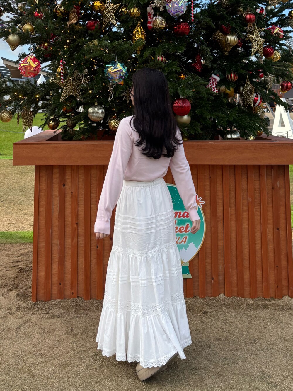 ピンク系のニット/セーター、ホワイト系のスカートを着用したレディースの冬コーディネートの1枚目の写真