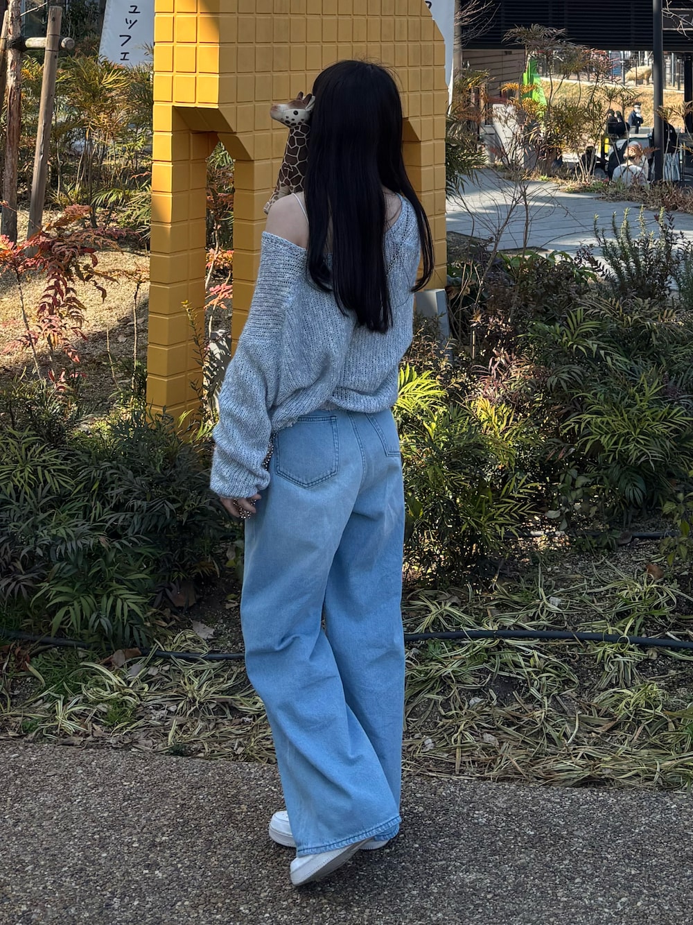 ブルー系のワンピース、ブルー系のデニムパンツ、ホワイト系のスニーカーを着用したレディースの春コーディネートの1枚目の写真