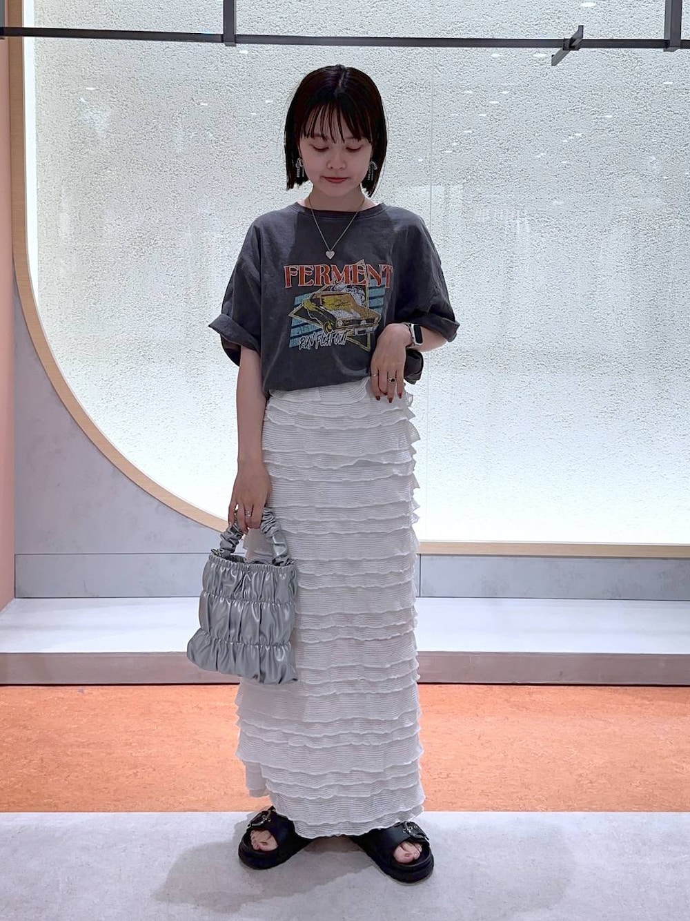 ホワイト系のスカート、グレー系のショルダーバッグ、グレー系のTシャツ/カットソーを着用したレディースの夏コーディネートの1枚目の写真