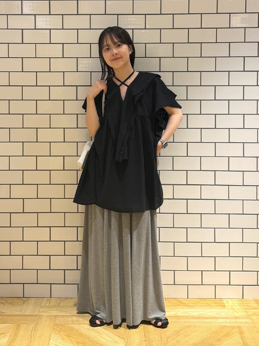 ホワイト系のショルダーバッグ、ブラック系のシャツ/ブラウス、ブラック系のサンダルを着用したレディースの夏コーディネートの1枚目の写真