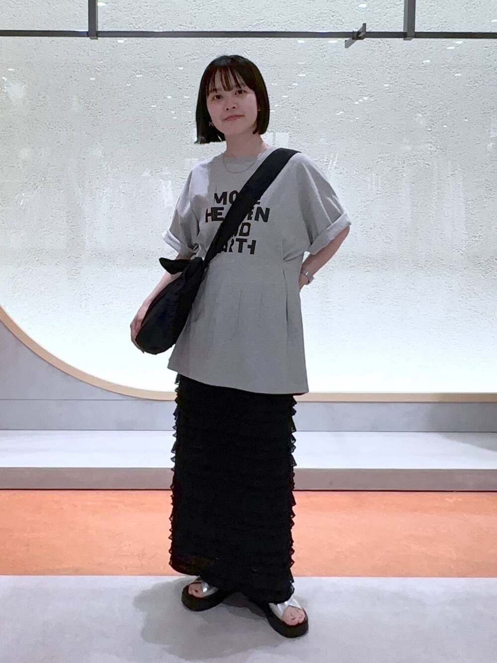 ブラック系のスカート、ブラック系のショルダーバッグ、シルバー系のサンダルを着用したレディースの夏コーディネートの1枚目の写真