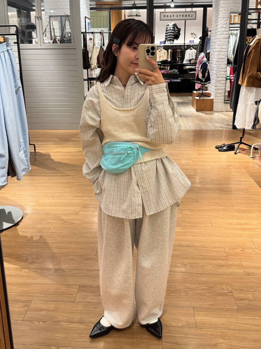 グレー系のスウェットパンツ、ブラック系のパンプス、ブルー系のボディバッグ/ウエストポーチを着用したレディースの春コーディネートの1枚目の写真