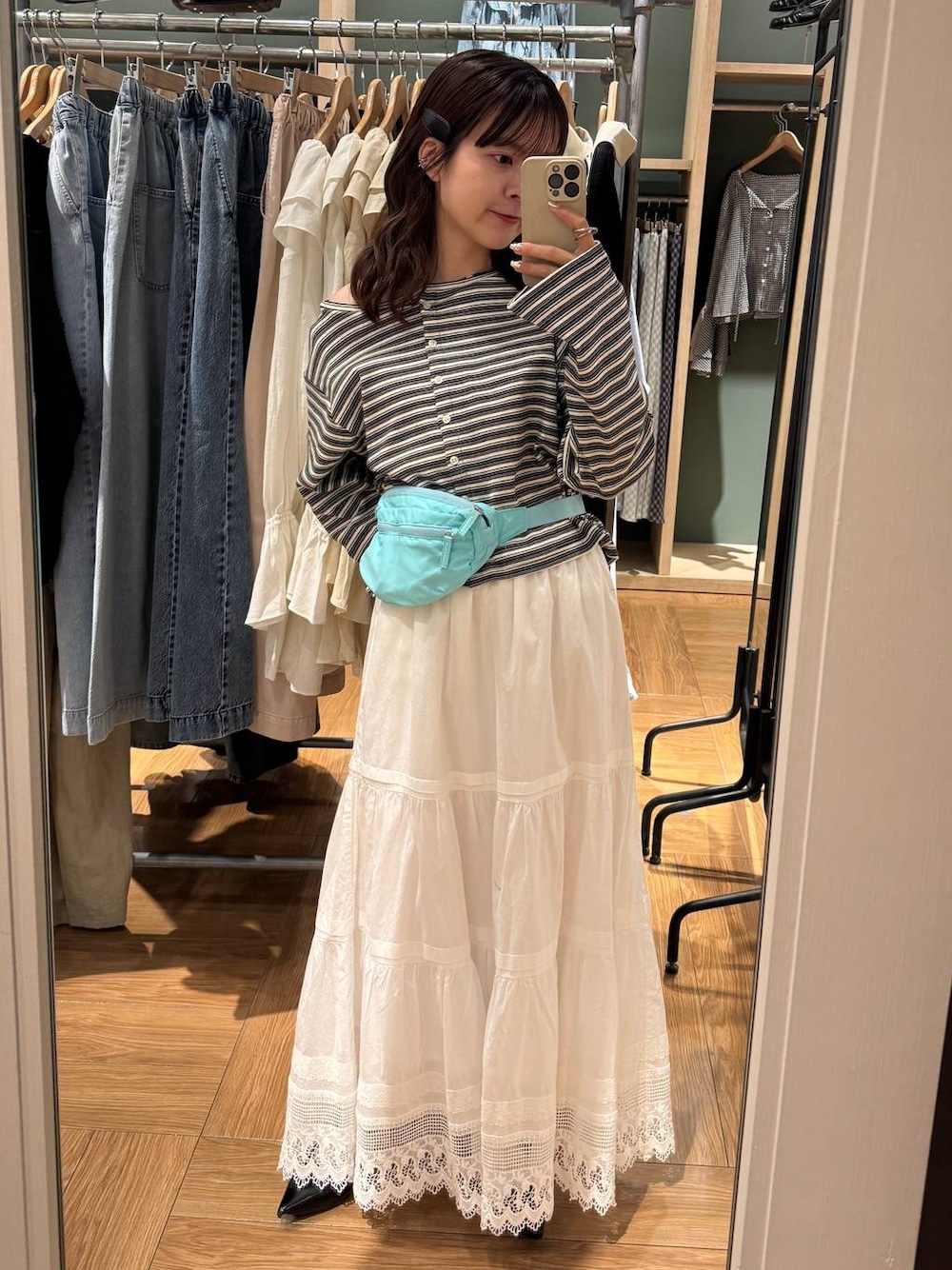 ブラック系のパンプス、ブルー系のボディバッグ/ウエストポーチ、グレー系のカーディガン/ボレロを着用したレディースの春コーディネートの1枚目の写真