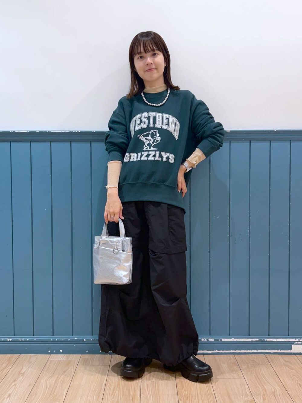 ブラック系のブーツ、グリーン系のスウェット、シルバー系のショルダーバッグを着用したレディースの秋コーディネートの1枚目の写真