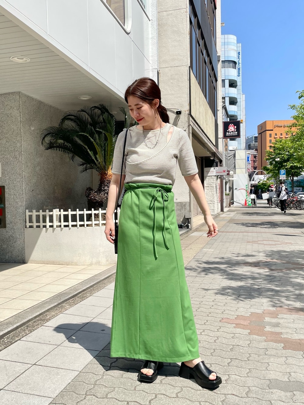 ホワイト系のTシャツ/カットソー、グリーン系のワンピース、ブラック系のサンダルを着用したレディースの春コーディネートの1枚目の写真