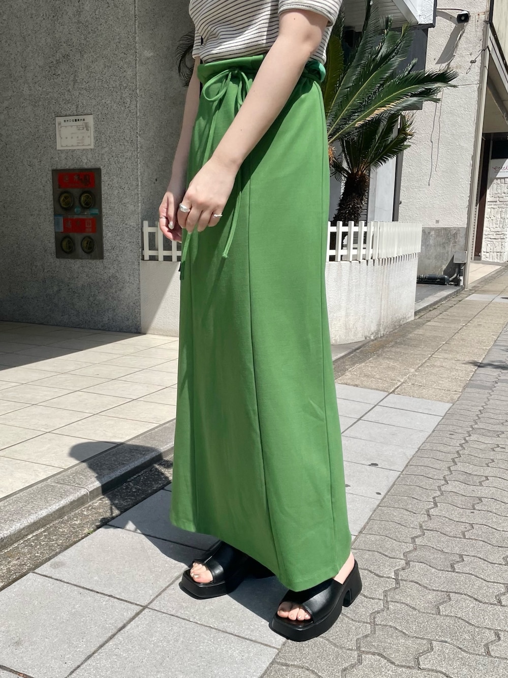 ホワイト系のTシャツ/カットソー、グリーン系のワンピース、ブラック系のサンダルを着用したレディースの春コーディネートの3枚目の写真