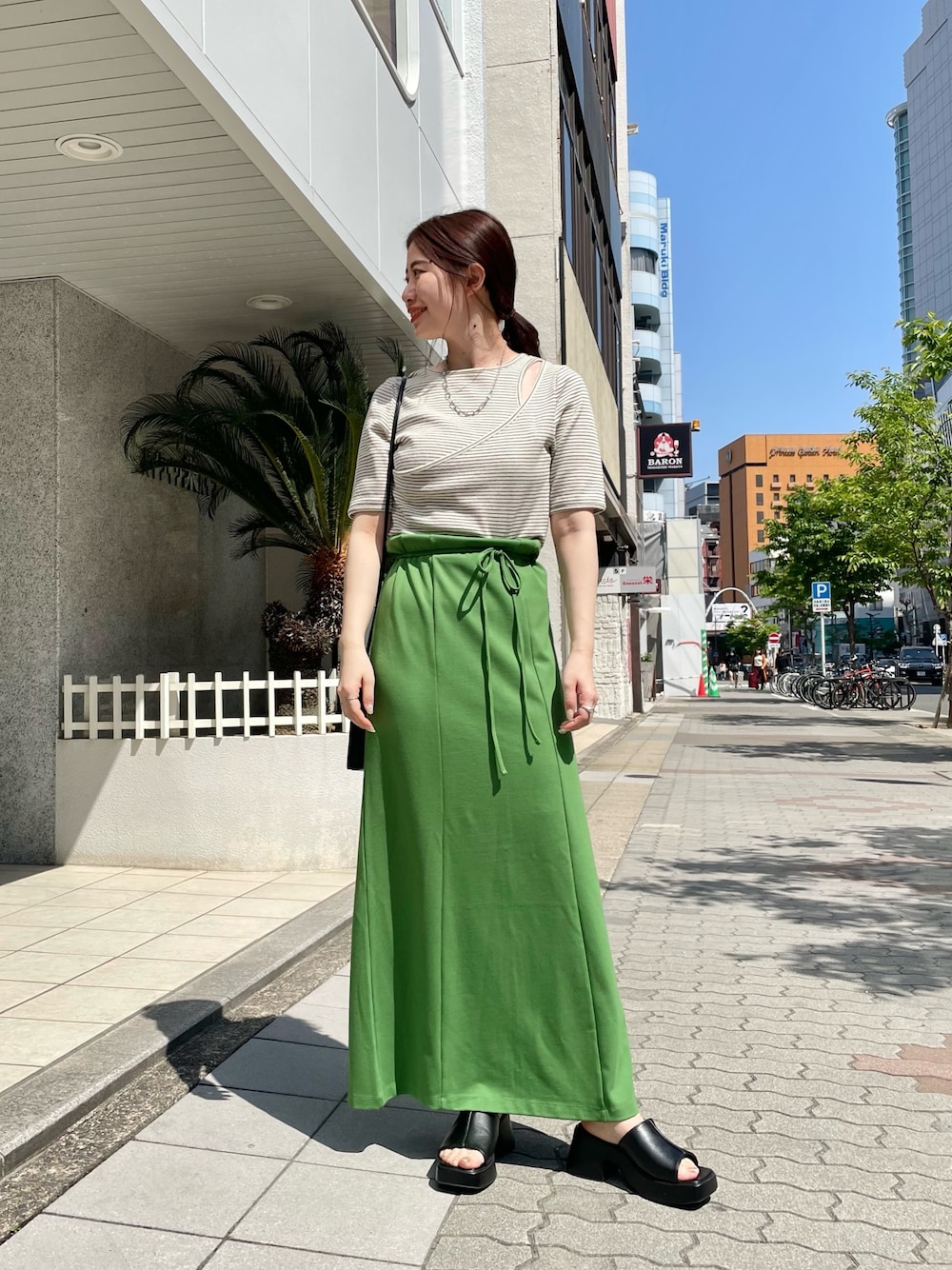 ホワイト系のTシャツ/カットソー、グリーン系のワンピース、ブラック系のサンダルを着用したレディースの春コーディネートの2枚目の写真