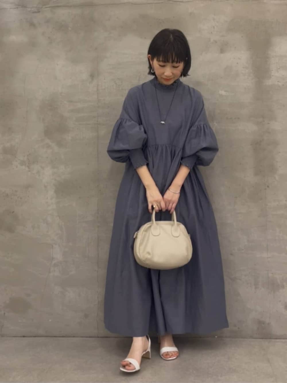 グレー系のボストンバッグ、グレー系のワンピースを着用したレディースの冬コーディネートの1枚目の写真