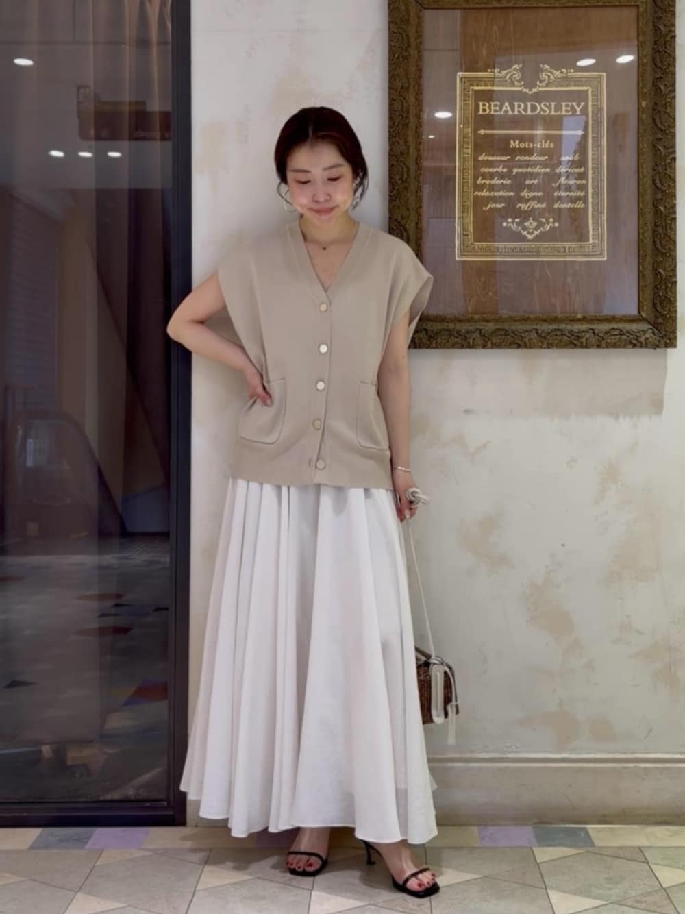 ホワイト系のスカート、ベージュ系のカーディガン/ボレロを着用したレディースの春コーディネートの1枚目の写真