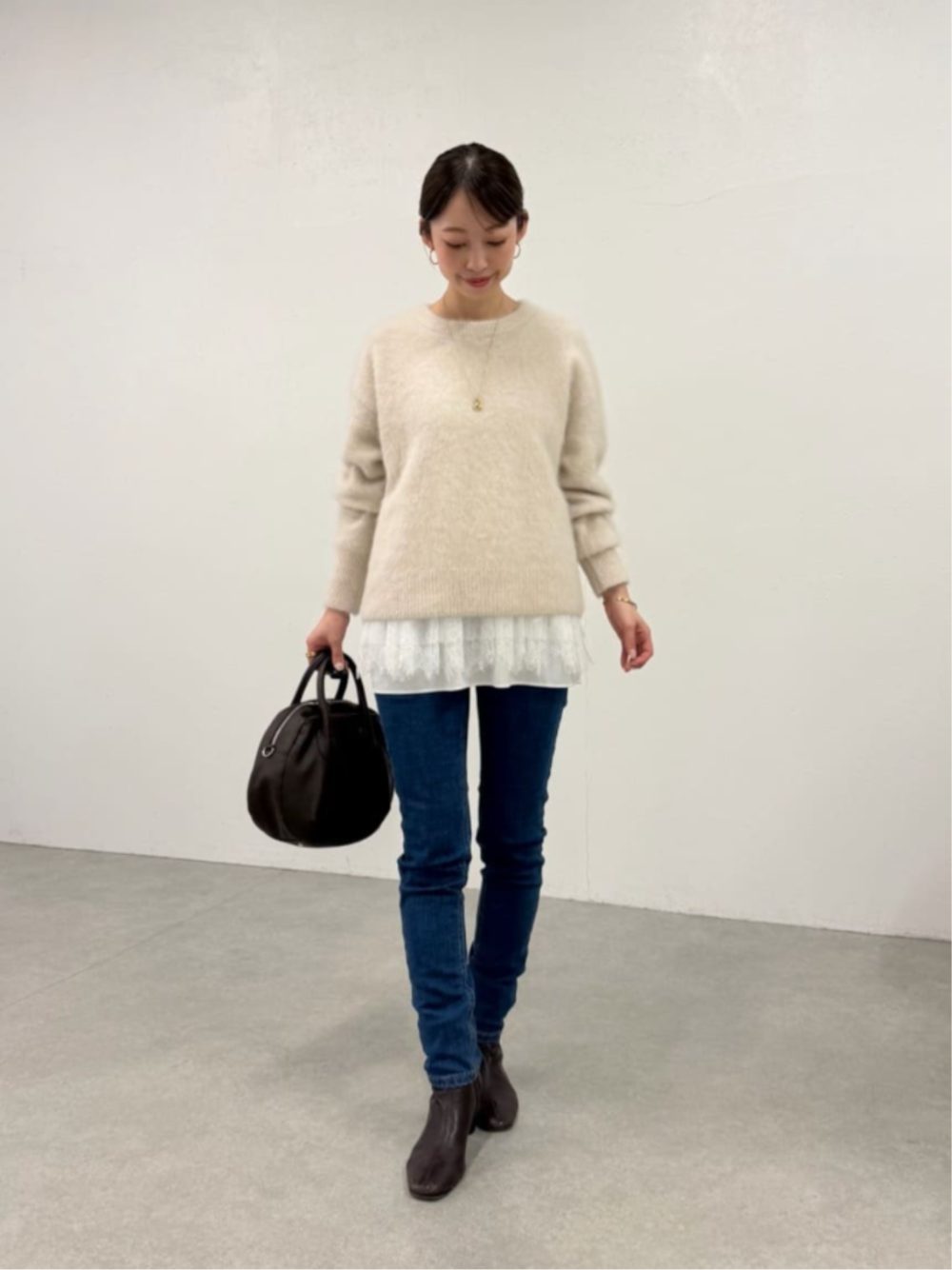 ブルー系のデニムパンツ、ホワイト系のタンクトップ、ホワイト系のニット/セーターを着用したレディースの秋コーディネートの1枚目の写真