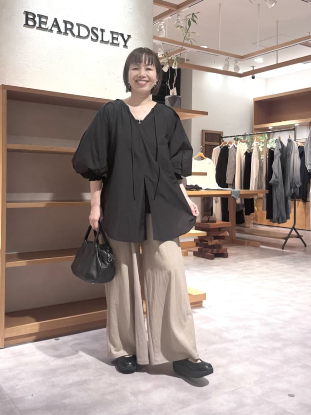 ブラック系のボストンバッグ、ベージュ系のその他パンツ、ブラック系のシャツ/ブラウスを着用したレディースの春コーディネートの1枚目の写真
