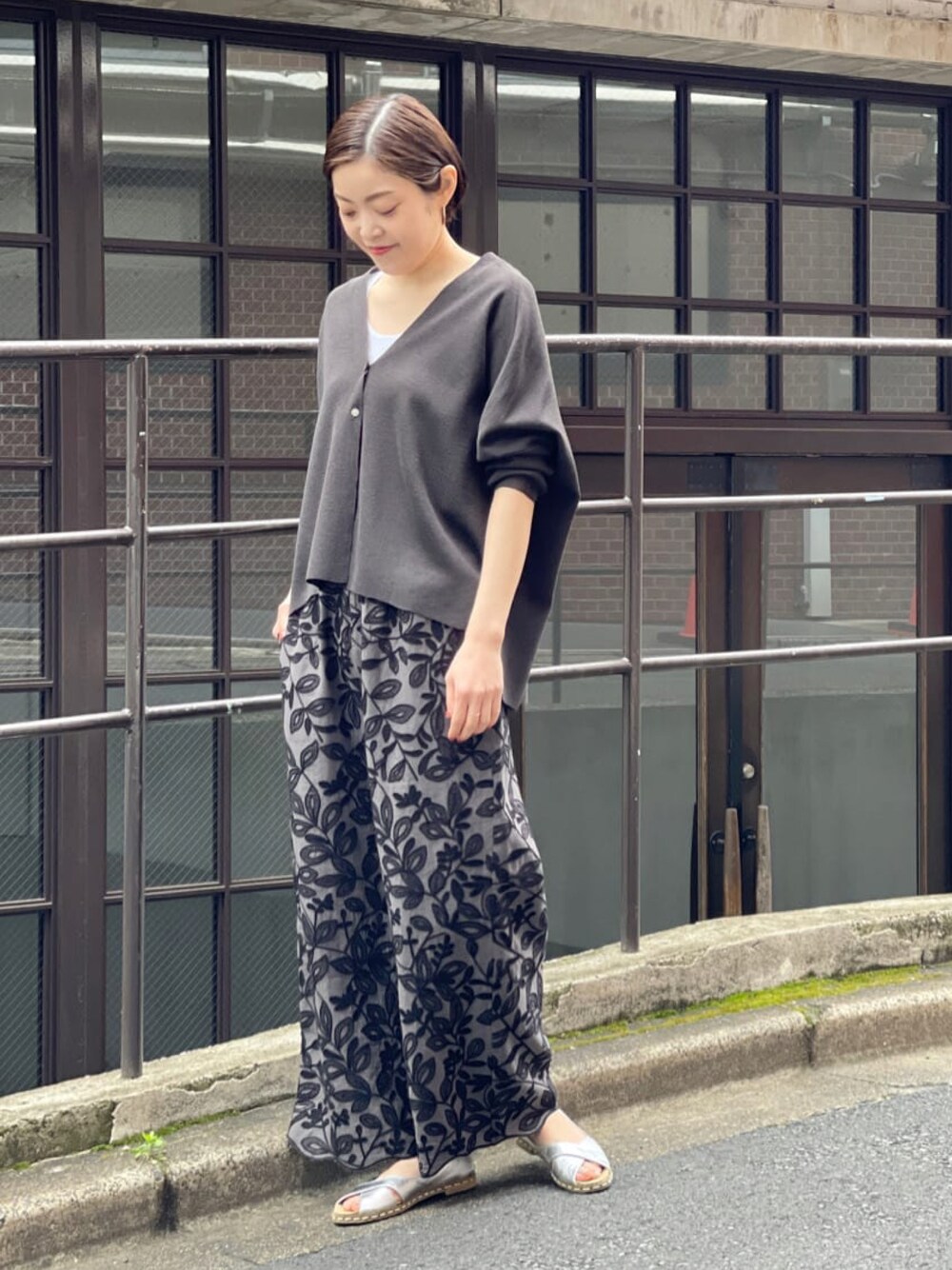ブラック系のカーディガン/ボレロ、グレー系のその他パンツ、シルバー系のサンダルを着用したレディースの春コーディネートの1枚目の写真