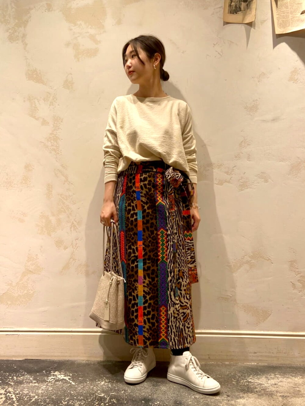 ベージュ系のトートバッグ、ホワイト系のニット/セーター、ホワイト系のスニーカーを着用したレディースの春コーディネートの1枚目の写真