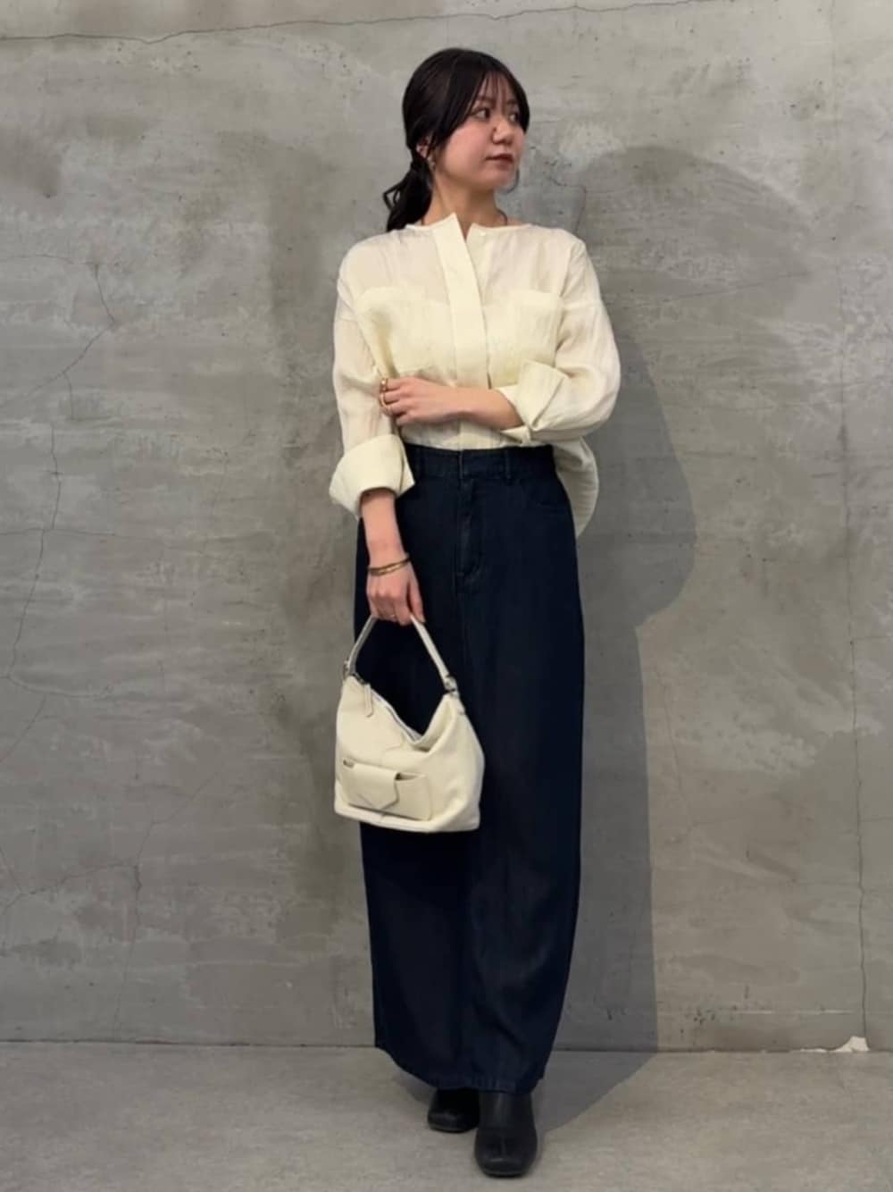 ブルー系のスカート、ホワイト系のトートバッグ、イエロー系のシャツ/ブラウスを着用したレディースの冬コーディネートの1枚目の写真