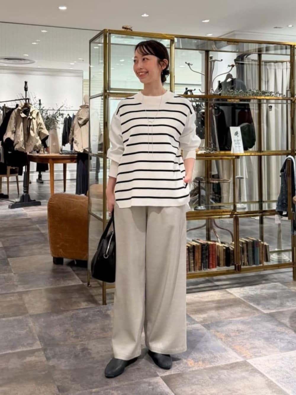 ブラック系のボストンバッグ、ホワイト系のニット/セーター、グレー系のその他パンツを着用したレディースの冬コーディネートの1枚目の写真