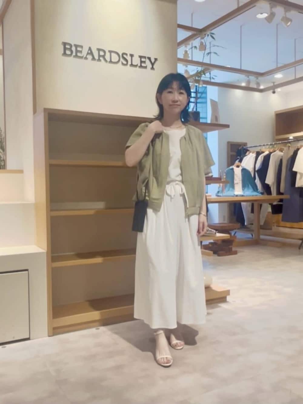 ブラック系のショルダーバッグ、ホワイト系のその他パンツ、グリーン系のベストを着用したレディースの春コーディネートの1枚目の写真