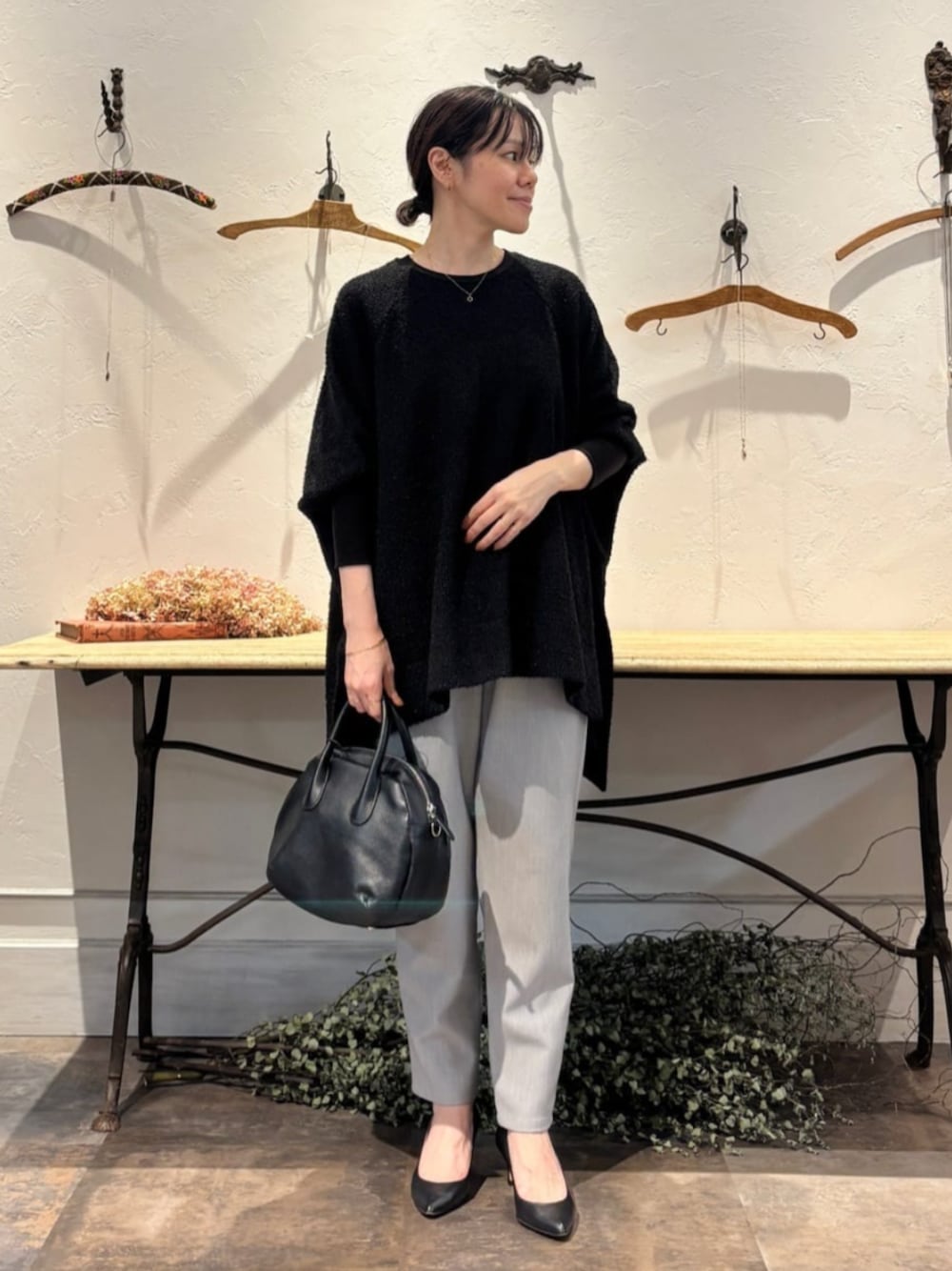 ブラック系のボストンバッグ、ブラック系のニット/セーター、グレー系のその他パンツを着用したレディースの秋コーディネートの1枚目の写真