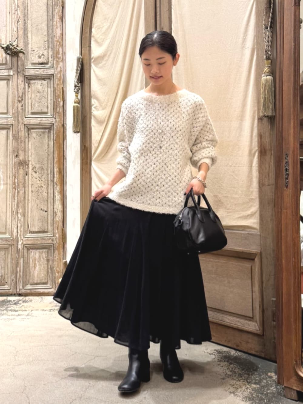 ブラック系のスカート、ホワイト系のニット/セーターを着用したレディースの秋コーディネートの1枚目の写真