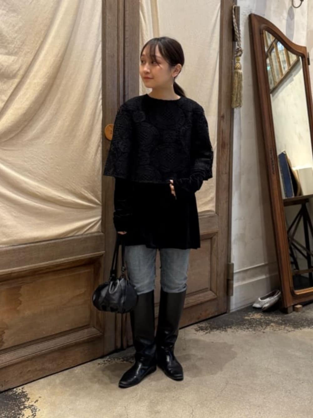 ブルー系のデニムパンツ、ブラック系のTシャツ/カットソー、ブラック系のポンチョを着用したレディースの冬コーディネートの1枚目の写真