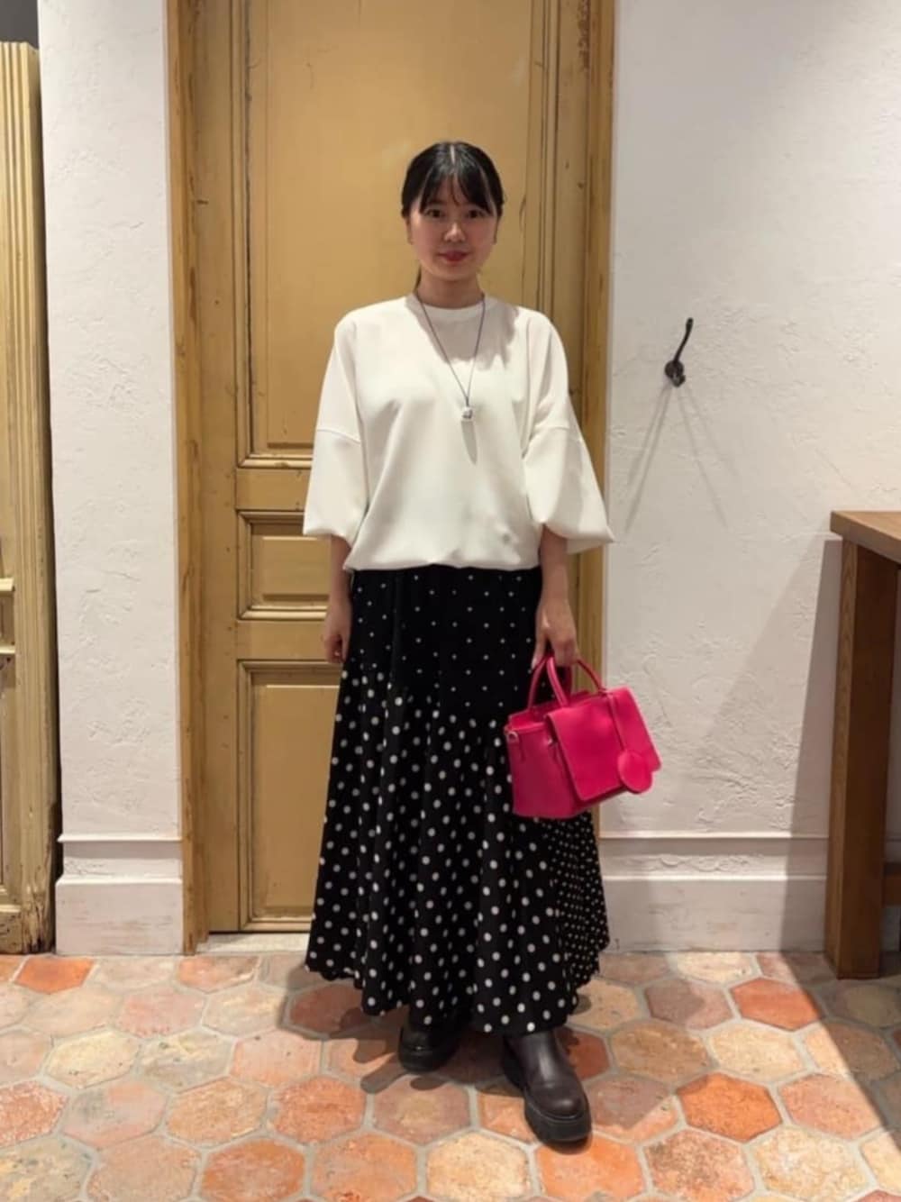 ブラック系のスカート、ピンク系のハンドバッグ、ホワイト系のシャツ/ブラウスを着用したレディースの冬コーディネートの1枚目の写真