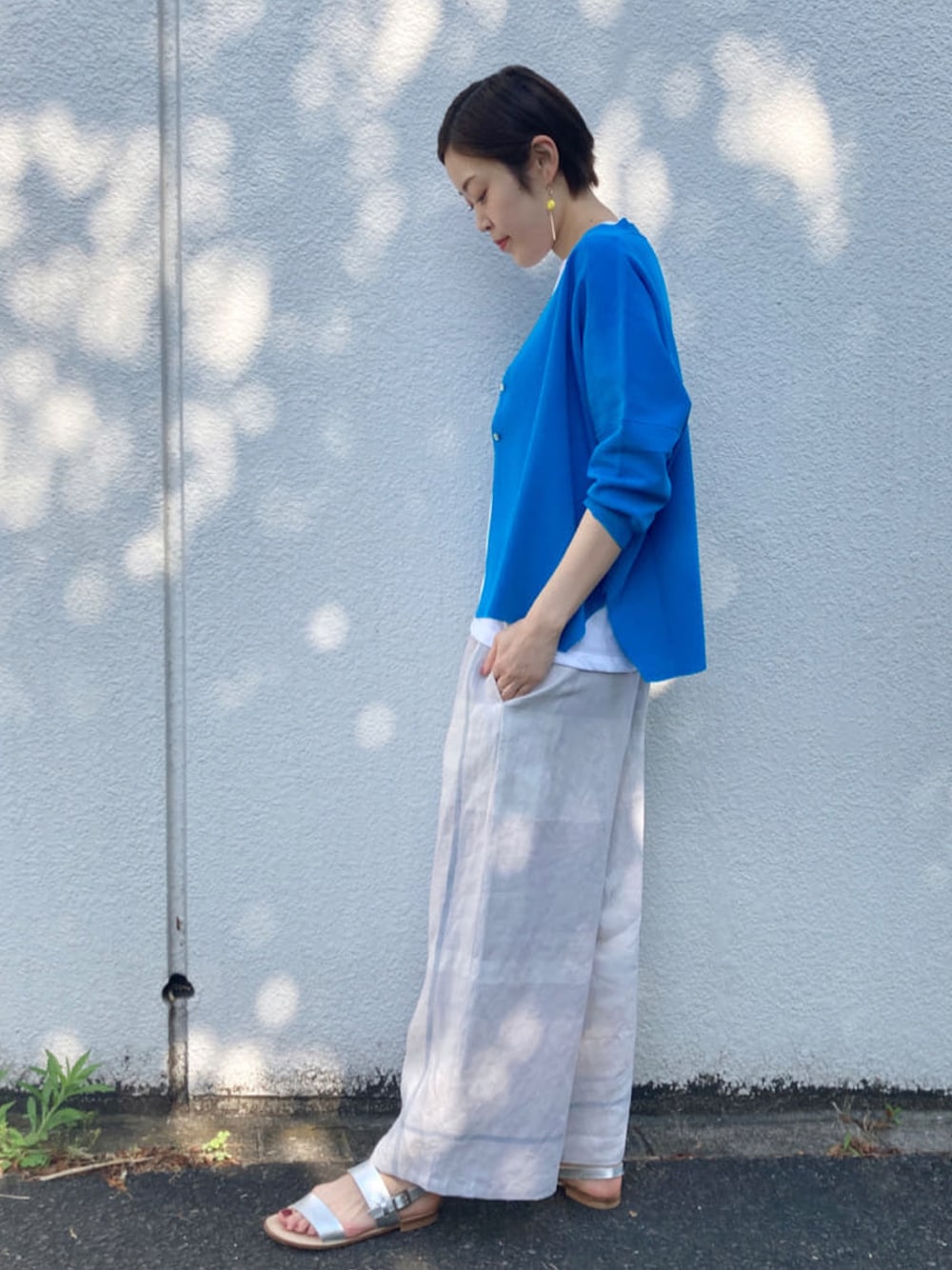 グレー系のその他パンツ、ホワイト系のTシャツ/カットソー、シルバー系のサンダルを着用したレディースの春コーディネートの1枚目の写真