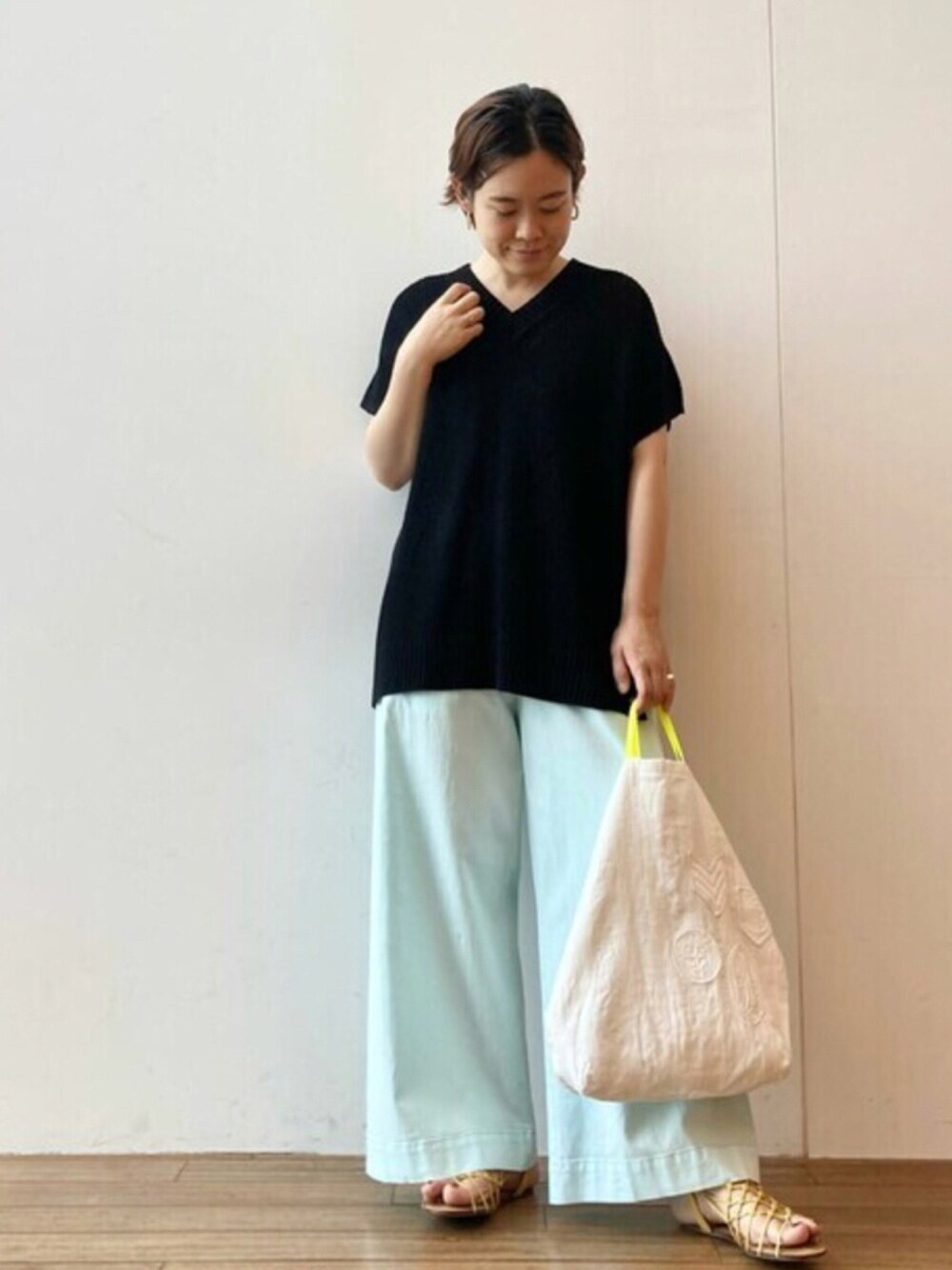 ブラック系のニット/セーター、グリーン系のその他パンツ、ホワイト系のトートバッグを着用したレディースの夏コーディネートの1枚目の写真