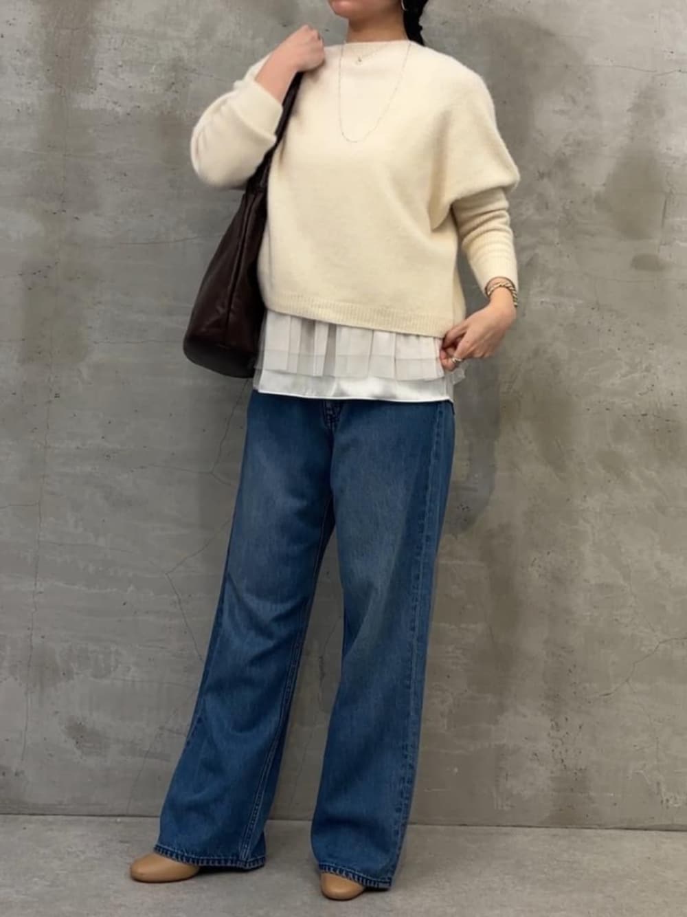 ブラック系のトートバッグ、ブルー系のデニムパンツ、ホワイト系のニット/セーターを着用したレディースの冬コーディネートの1枚目の写真