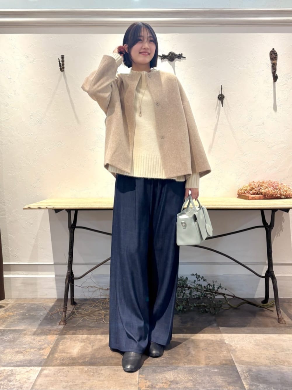 ブルー系のその他パンツ、グリーン系のハンドバッグ、ホワイト系のニット/セーターを着用したレディースの冬コーディネートの1枚目の写真