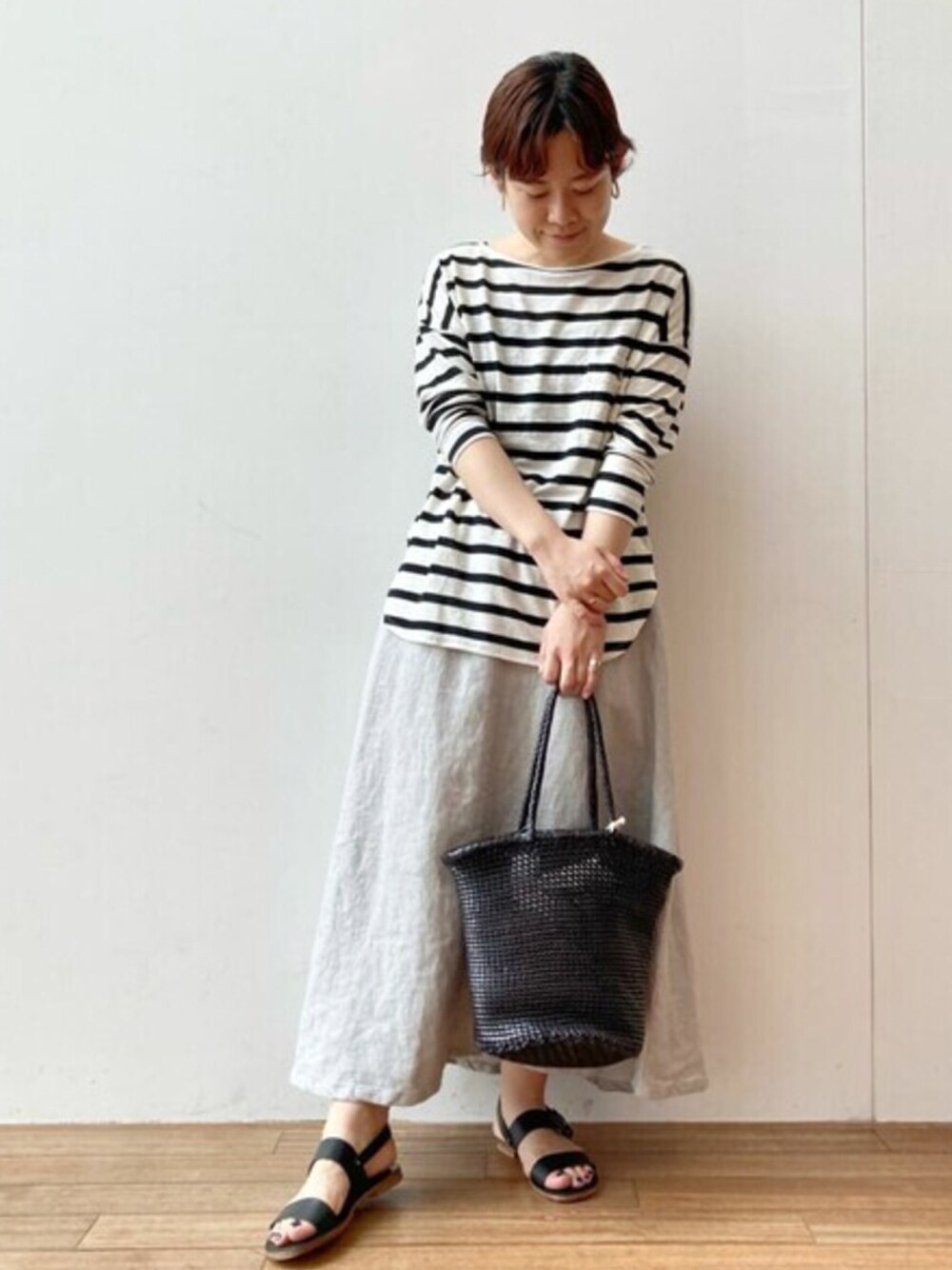 ホワイト系のTシャツ/カットソー、グレー系のスカート、ブラック系のトートバッグを着用したレディースの夏コーディネートの1枚目の写真