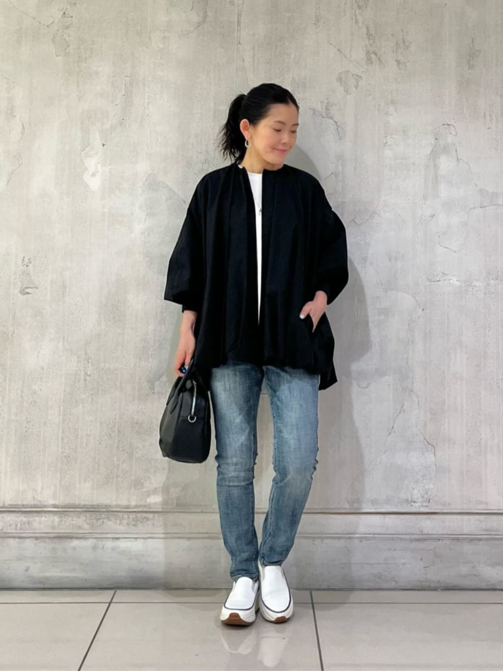 ホワイト系のスニーカー、ブルー系のデニムパンツ、ブラック系のボストンバッグを着用したレディースの冬コーディネートの1枚目の写真