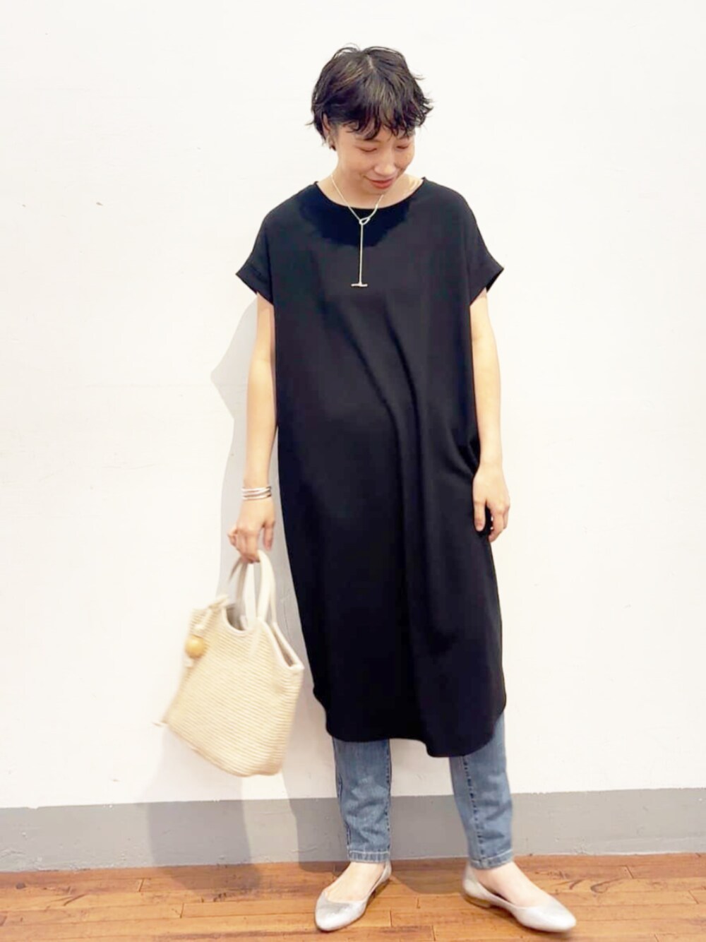 ブルー系のデニムパンツ、ホワイト系のトートバッグ、ブラック系のワンピースを着用したレディースの夏コーディネートの1枚目の写真