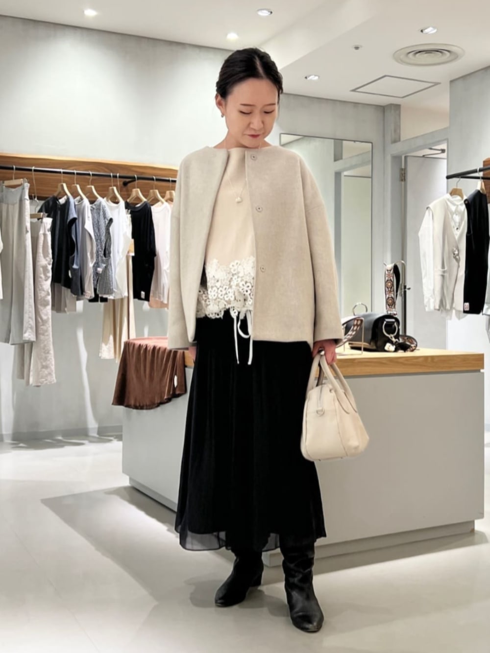 グレー系のノーカラーコート、ベージュ系のニット/セーター、ブラック系のその他パンツを着用したレディースの秋コーディネートの1枚目の写真