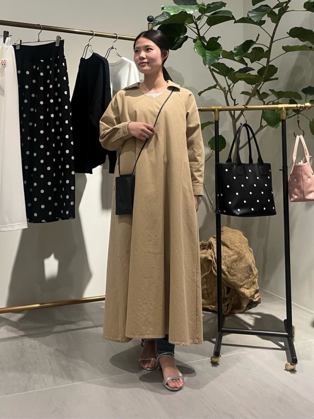 ブラック系のショルダーバッグ、ベージュ系のワンピースを着用したレディースの春コーディネートの1枚目の写真