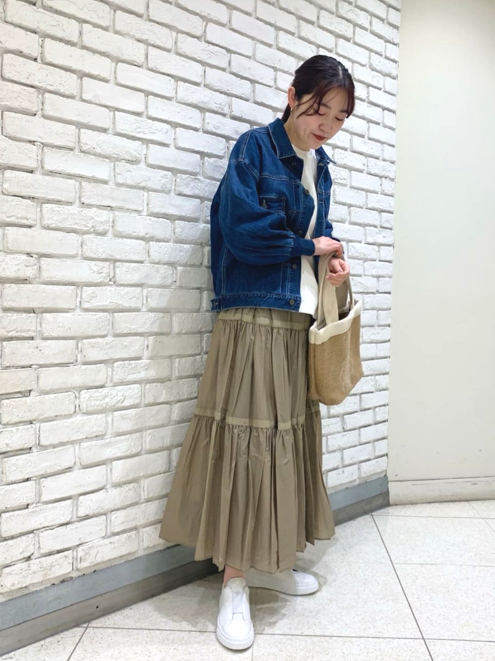 ブルー系のデニムジャケット、ホワイト系のTシャツ/カットソー、ベージュ系のスカートを着用したレディースの冬コーディネートの1枚目の写真