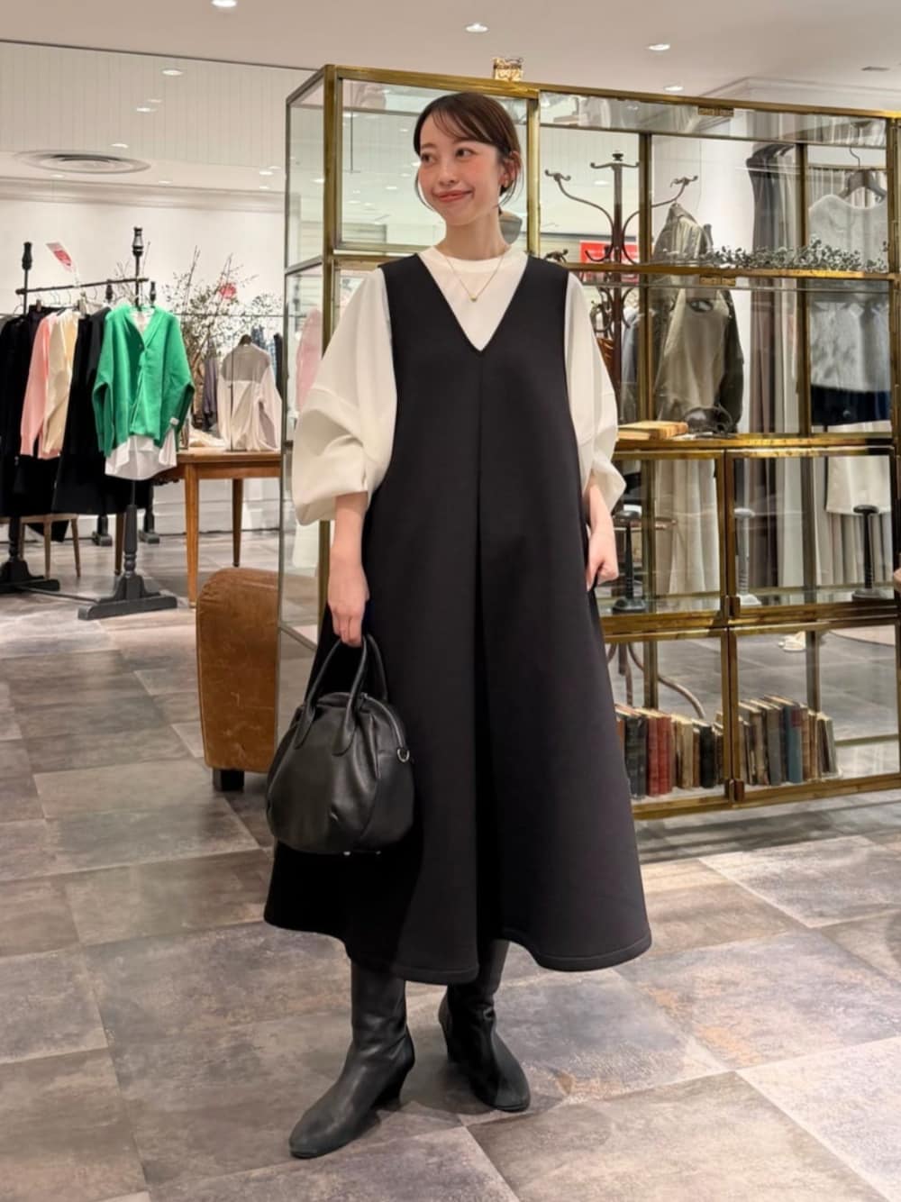 ブラック系のボストンバッグ、ホワイト系のシャツ/ブラウス、ブラック系のジャンパースカートを着用したレディースの冬コーディネートの1枚目の写真