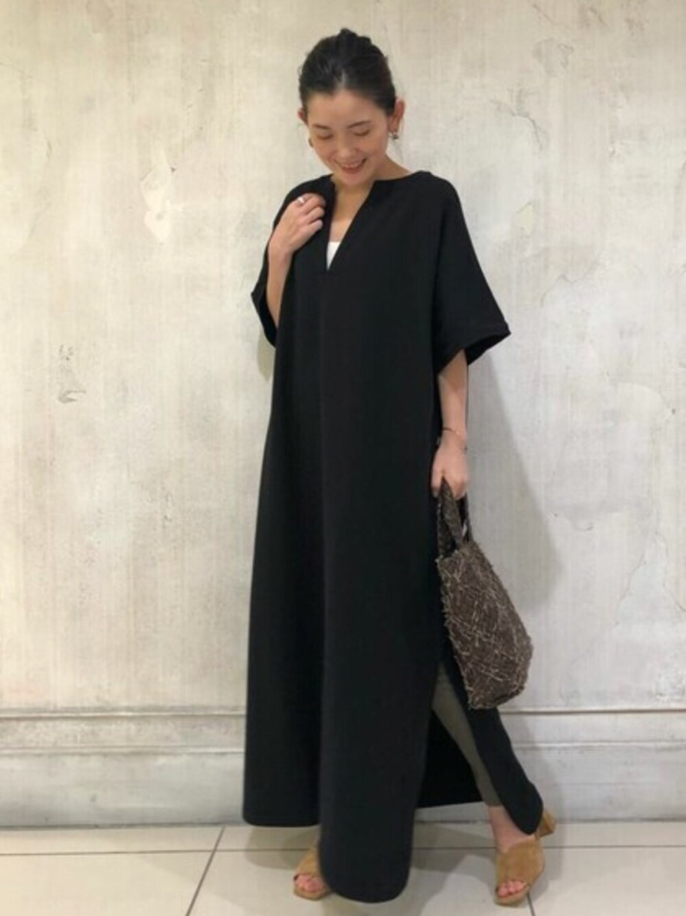 ブラック系のワンピース、ブラウン系のトートバッグ、イエロー系のサンダルを着用したレディースの夏コーディネートの1枚目の写真