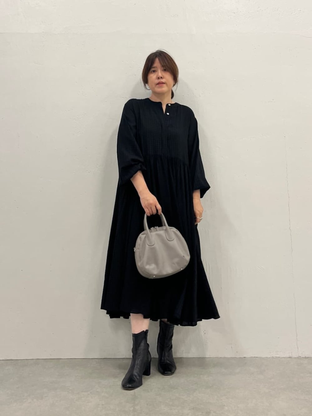 グレー系のボストンバッグ、ブラック系のワンピースを着用したレディースの夏コーディネートの1枚目の写真