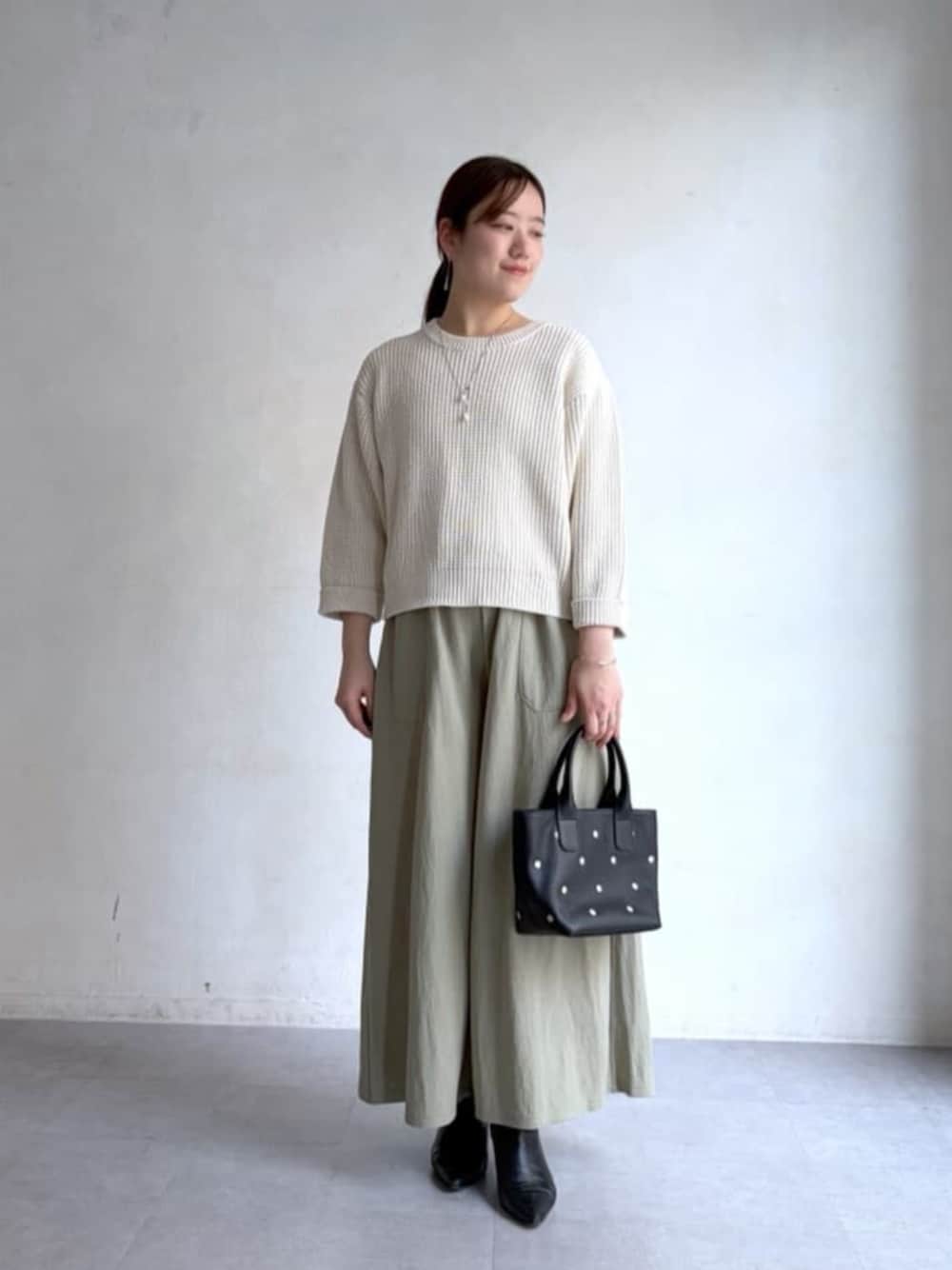 ホワイト系のニット/セーター、グリーン系のその他パンツ、ブラック系のトートバッグを着用したレディースの冬コーディネートの1枚目の写真