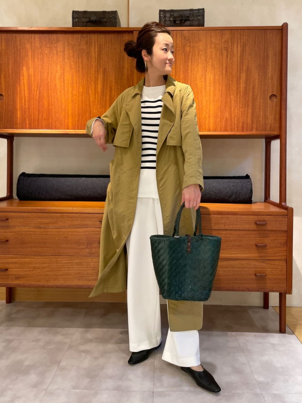 ベージュ系のその他アウター、ブラック系のニット/セーター、グリーン系のトートバッグを着用したレディースの春コーディネートの1枚目の写真